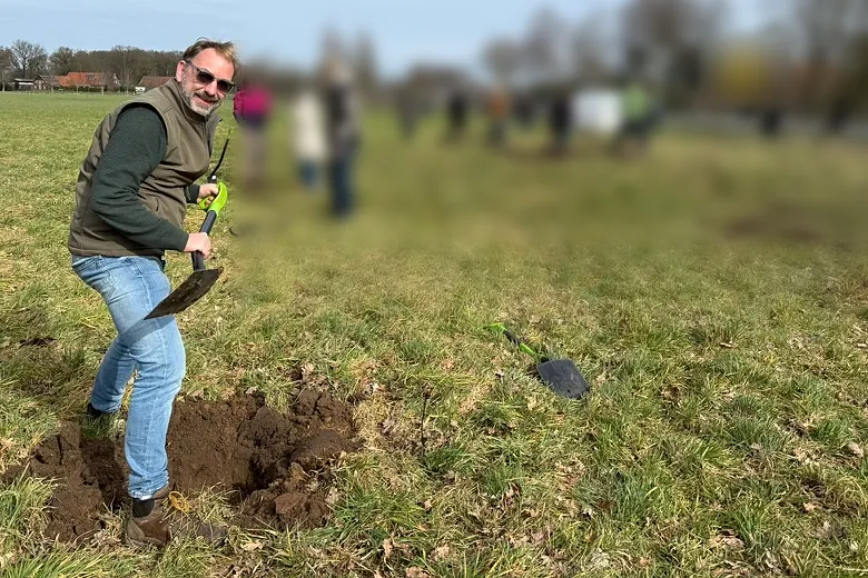 Bernhard Aumann gräbt mit dem Spaten ein Pflanzloch in Grünland, frische dunkle Erde